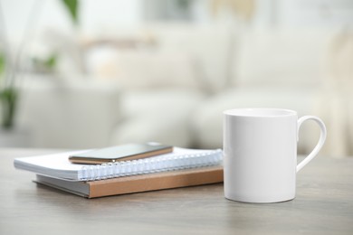 Photo of White ceramic mug and notebooks on wooden table indoors. Space for text