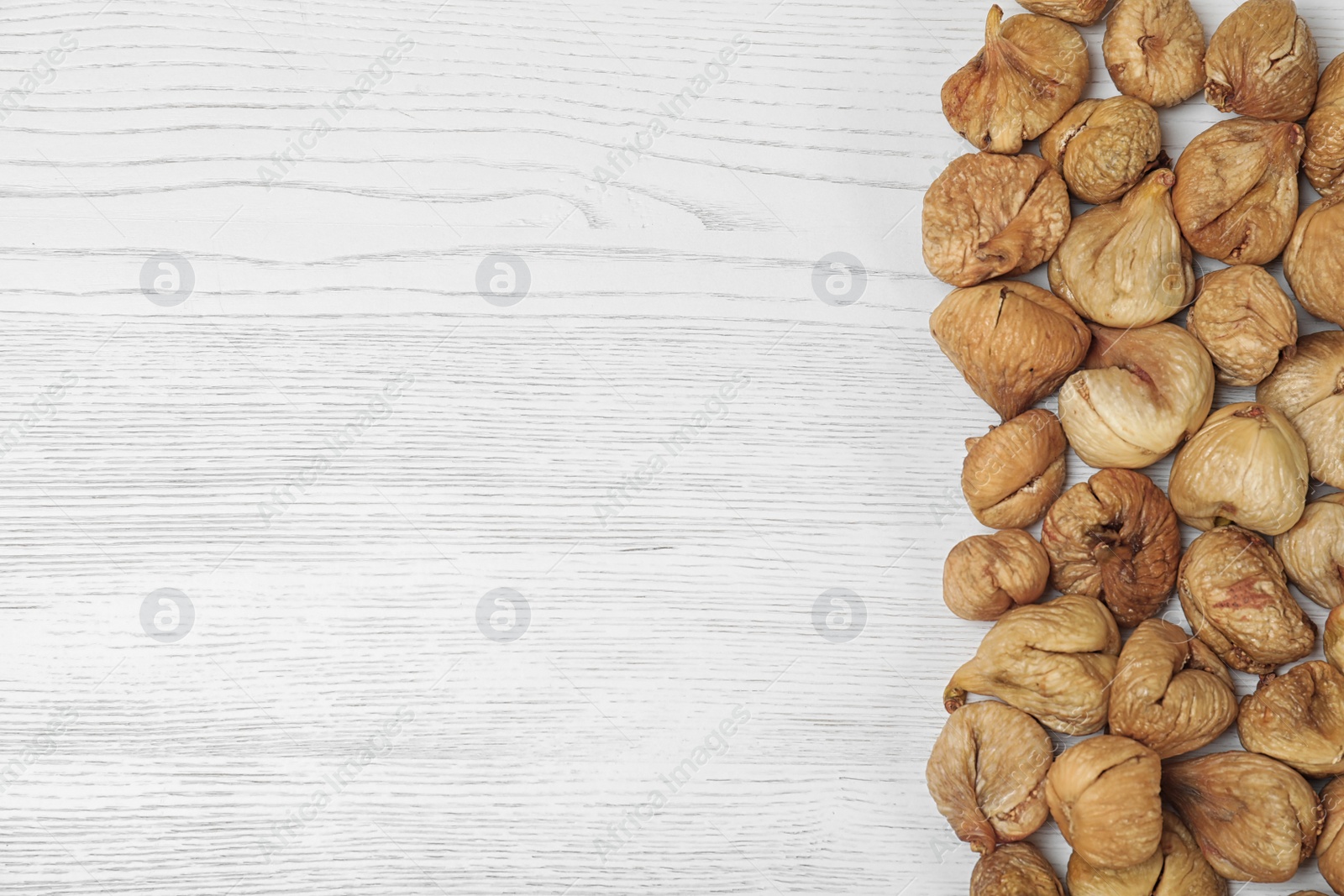 Photo of Dried figs on white wooden table, top view with space for text. Healthy fruit