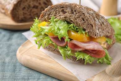 Photo of Tasty sandwich with ham on wooden table, closeup