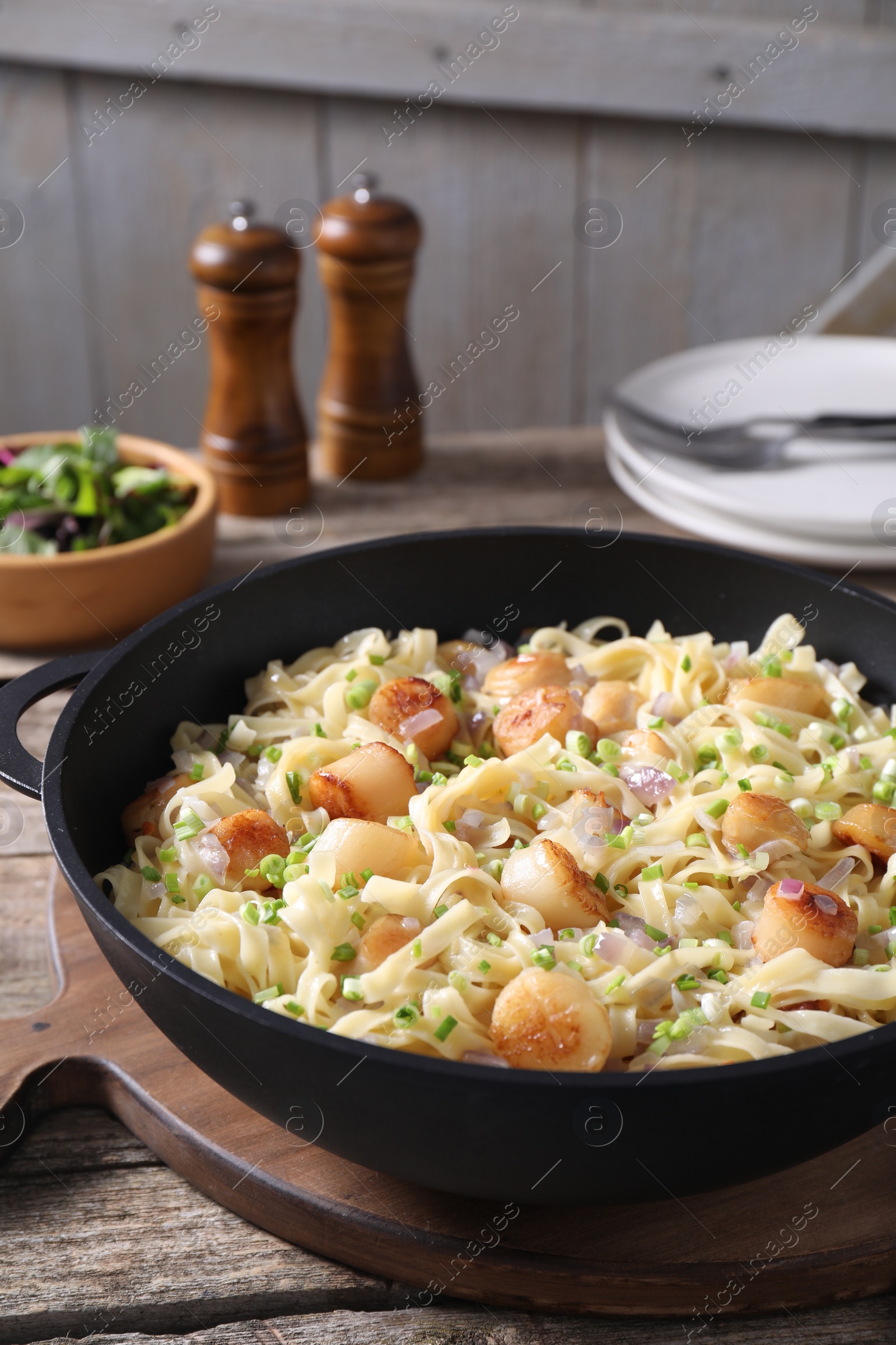 Photo of Delicious scallop pasta with onion in pan on table