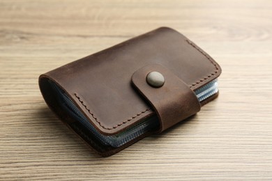 Photo of Leather business card holder on wooden table, closeup