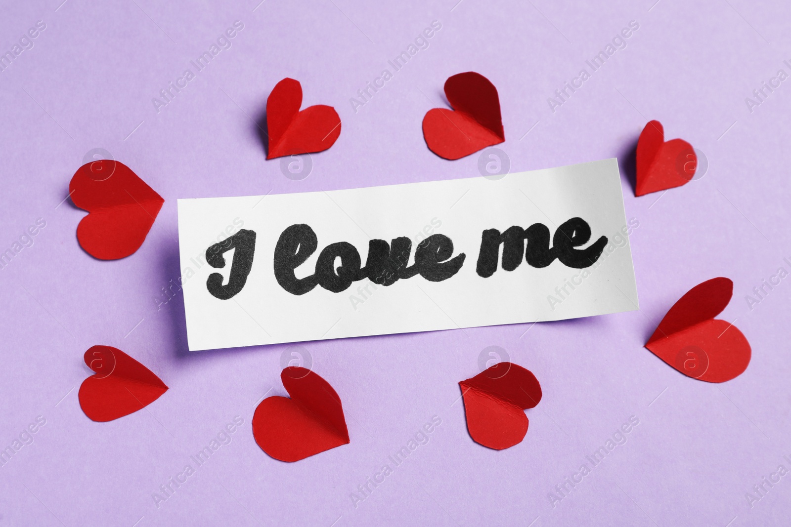 Photo of Paper with handwritten phrase I Love Me and red hearts on violet background, top view