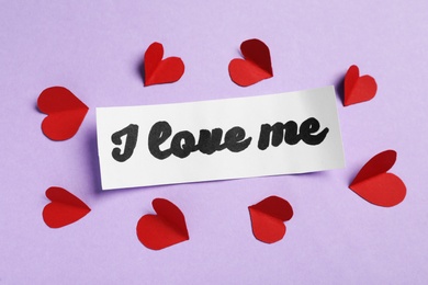 Paper with handwritten phrase I Love Me and red hearts on violet background, top view