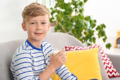 Adorable little boy with glass of milk at home