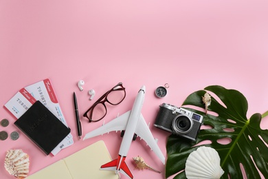 Photo of Flat lay composition with toy airplane and travel items on pink background. Space for text