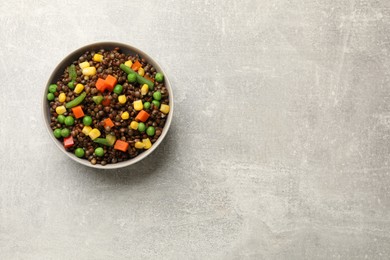 Delicious lentils with vegetables in bowl on light grey table, top view. Space for text