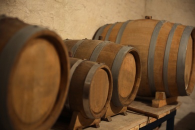 Photo of Different wooden barrels on table in wine cellar