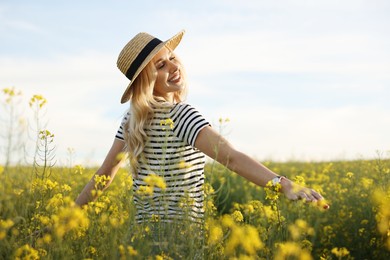 Happy young woman with straw hat in field on spring day