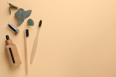 Photo of Flat lay composition with bamboo toothbrushes on pale orange background, space for text