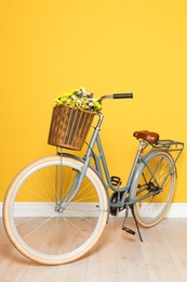 Retro bicycle with wicker basket near color wall