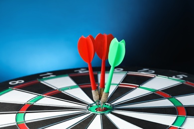 Photo of Arrows hitting target on dart board against blue background