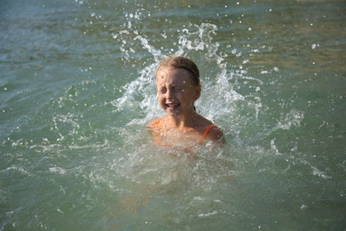 Photo of Emotional little girl having fun in sea on sunny day. Beach holiday