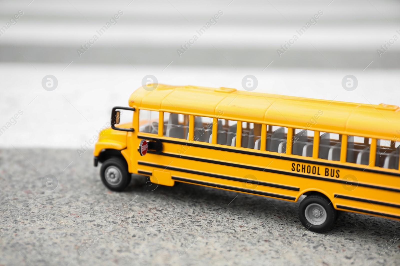 Photo of Yellow toy school bus on road outdoors. Transport for students