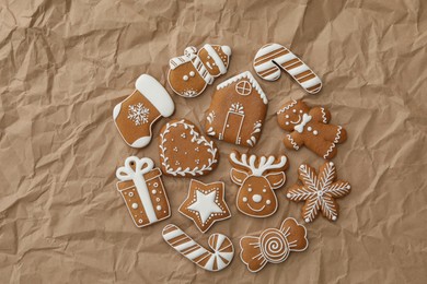 Photo of Different Christmas gingerbread cookies on crumpled parchment, flat lay