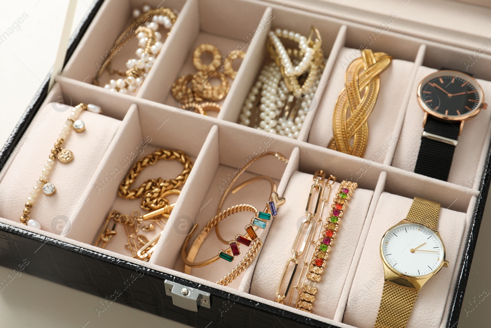 Photo of Elegant jewelry box with beautiful bijouterie and expensive wristwatches on table, closeup