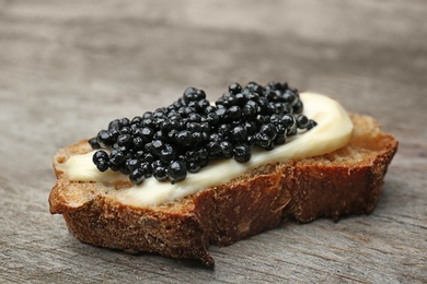 Sandwich with black caviar on wooden background