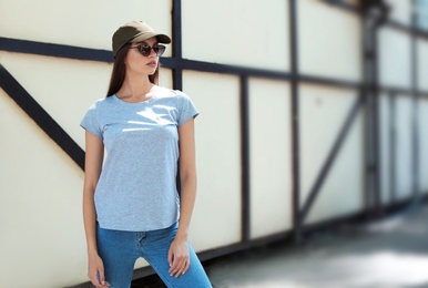 Photo of Young woman wearing gray t-shirt on street. Urban style