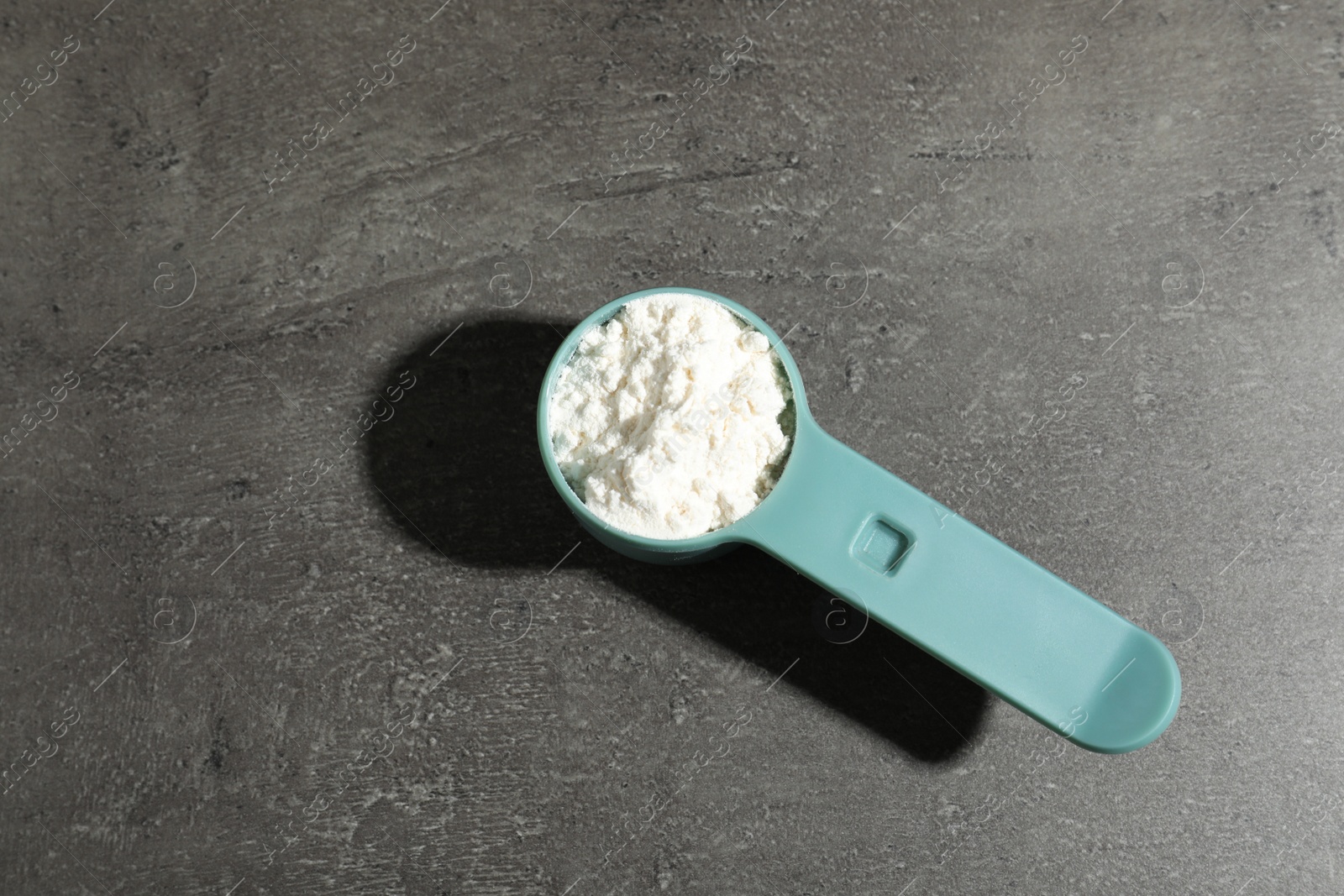 Photo of Scoop of protein powder on grey background, top view