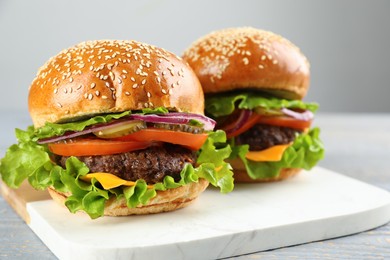 Photo of Tasty burgers on white marble board, closeup. Fast food