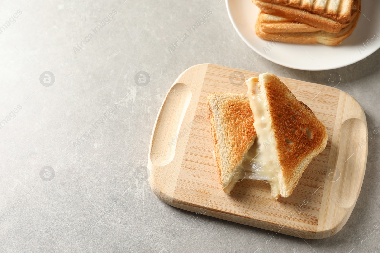 Photo of Wooden board with fresh cheese sandwiches on grey table, above view. Space for text