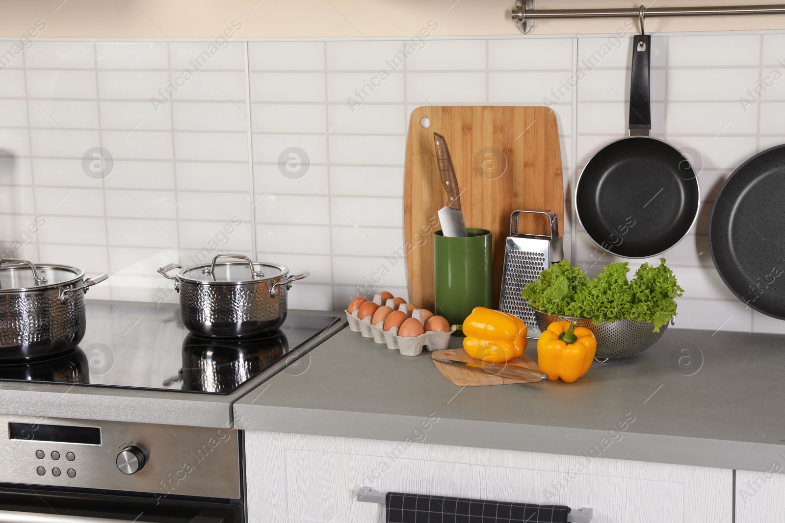 Photo of Set of clean cookware, utensils and products on table in modern kitchen