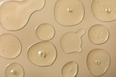 Photo of Drops of hydrophilic oil on beige background, flat lay