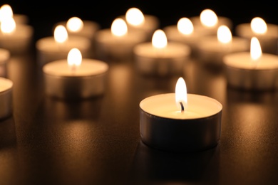 Burning candle on table in darkness, space for text. Funeral symbol