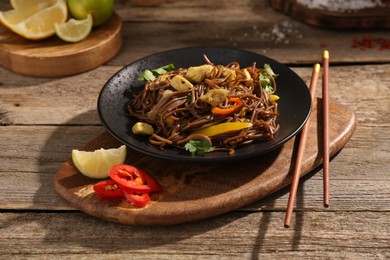 Photo of Stir-fry. Tasty noodles with meat and vegetables served on wooden table