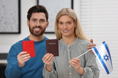 Immigration. Happy couple with passports and flag of Israel indoors