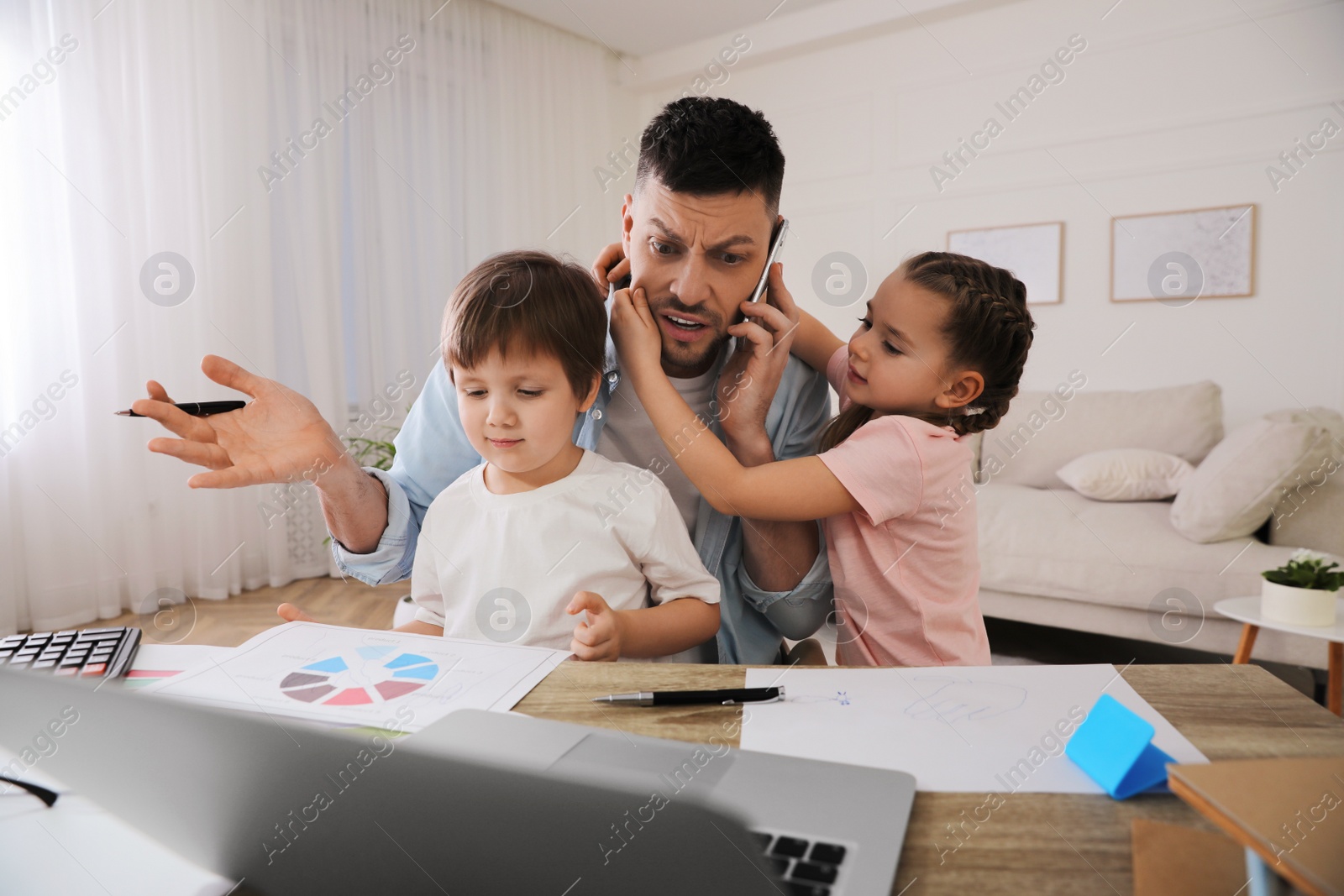 Photo of Overwhelmed man combining parenting and work at home