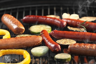 Photo of New modern barbecue grill with tasty sausages and vegetables, closeup