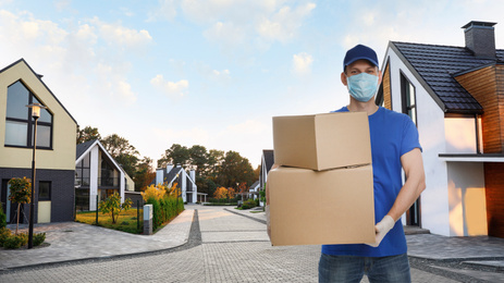Image of Courier in protective mask and gloves with boxes on street. Delivery service during coronavirus quarantine