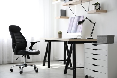 Photo of Comfortable office chair near table with modern computer