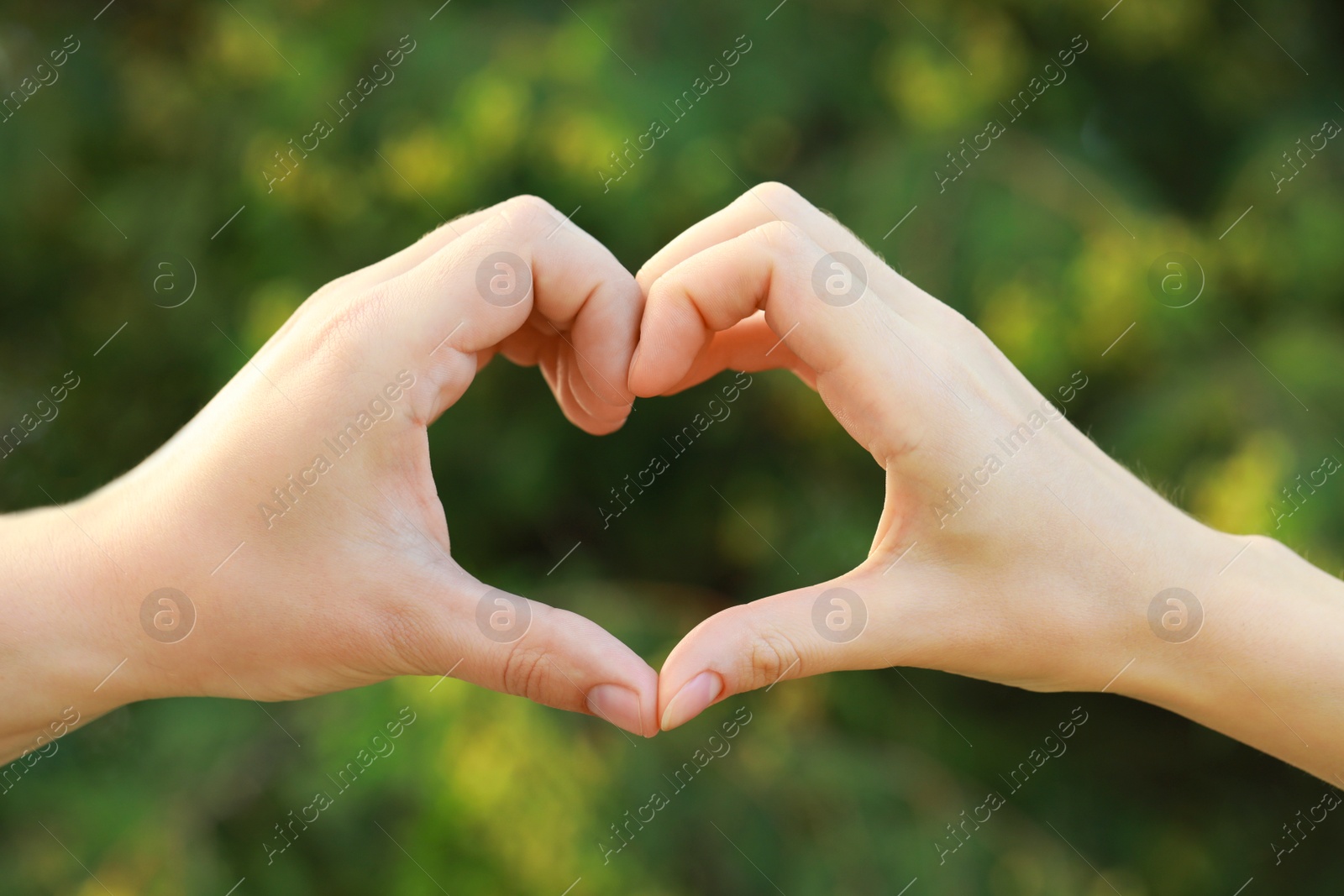 Photo of Couple making heart with hands outdoors on sunny day, closeup