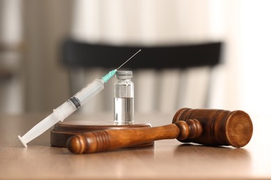 Photo of Law concept. Gavel, syringe and glass vial on wooden table