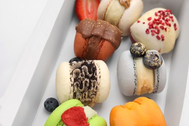 Photo of Cardboard box with delicious sweet macarons, closeup
