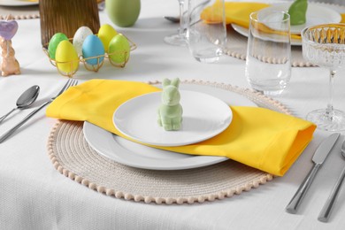 Festive table setting with cutlery, plate and bunny figure. Easter celebration