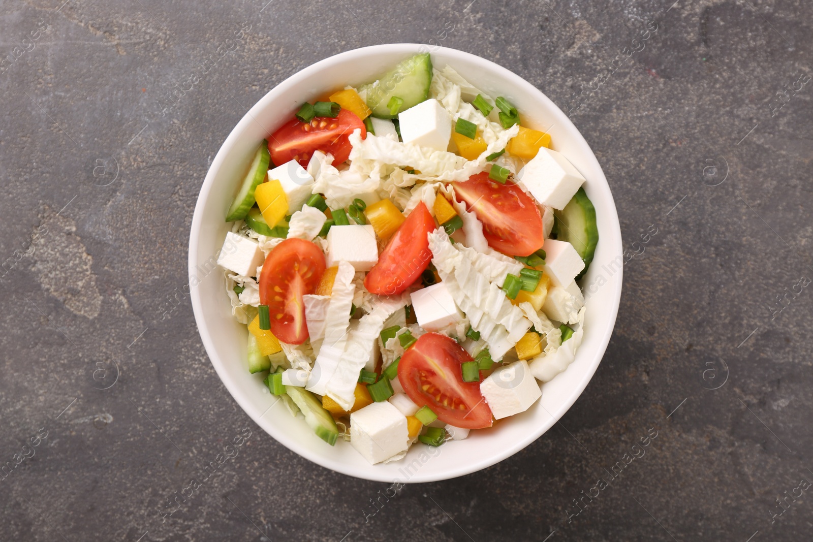 Photo of Tasty salad with Chinese cabbage, tomato, cheese, pepper and cucumber on grey table, top view