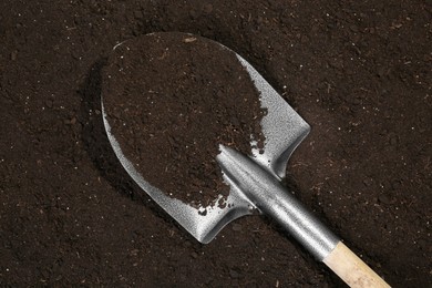 Photo of Metal shovel on fertile soil, top view. Gardening tool
