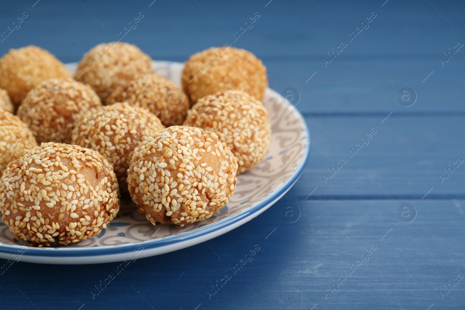 Photo of Delicious sesame balls on blue wooden table, closeup. Space for text