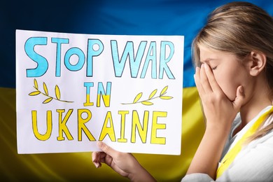 Photo of Sad woman holding poster with words Stop War in Ukraine near national flag