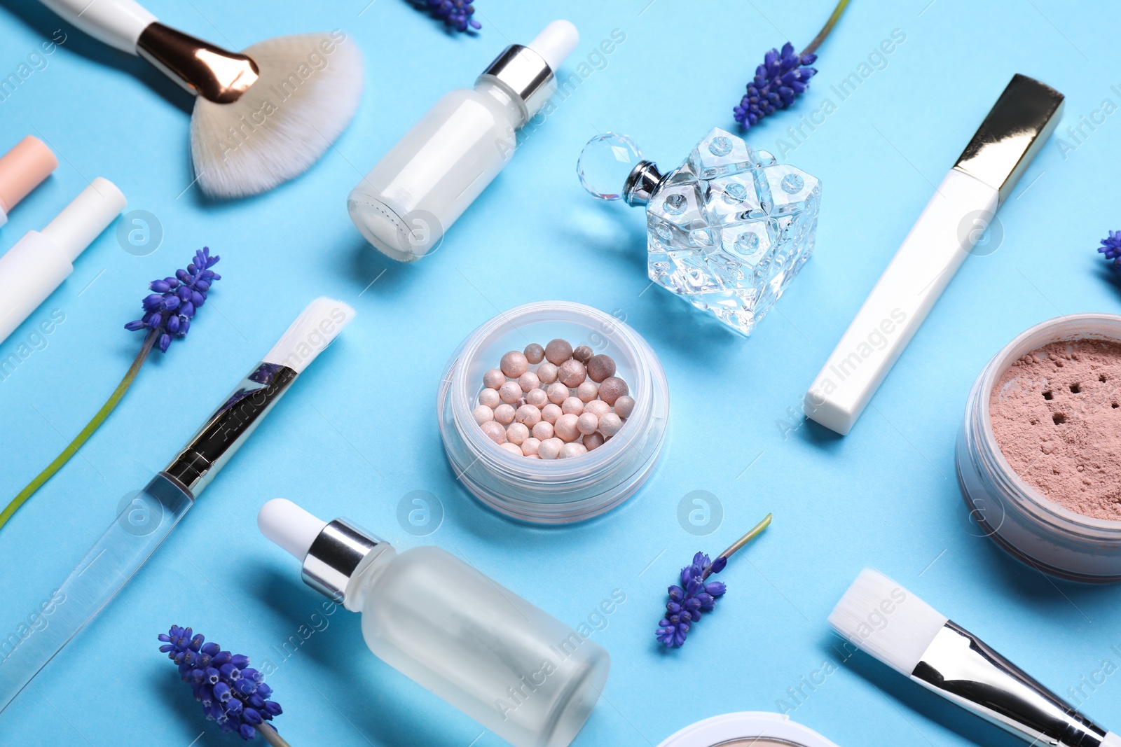 Photo of Composition with different makeup products and beautiful spring flowers on light blue background