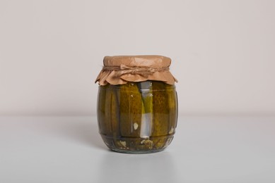 Photo of Jar of tasty pickled cucumbers on white table