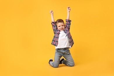 Photo of Happy little boy dancing on yellow background