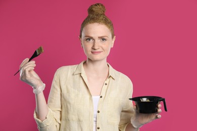 Young woman dyeing her hair with henna on pink background