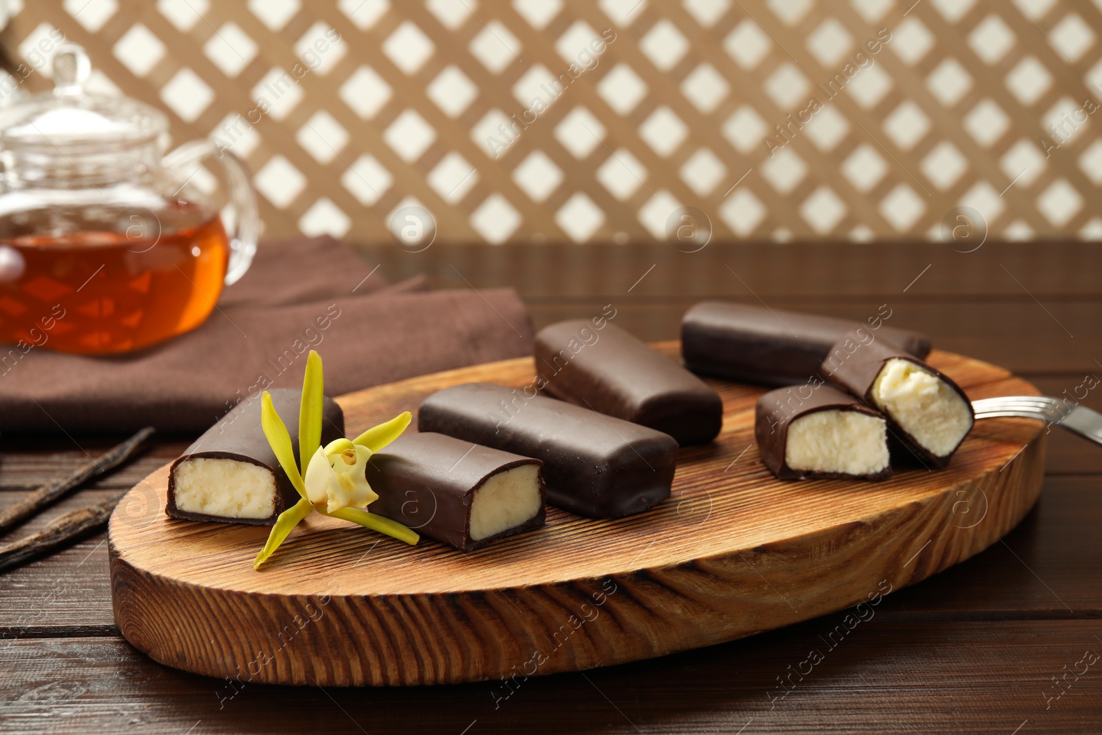 Photo of Glazed curd cheese bars and vanilla flower on wooden table, closeup