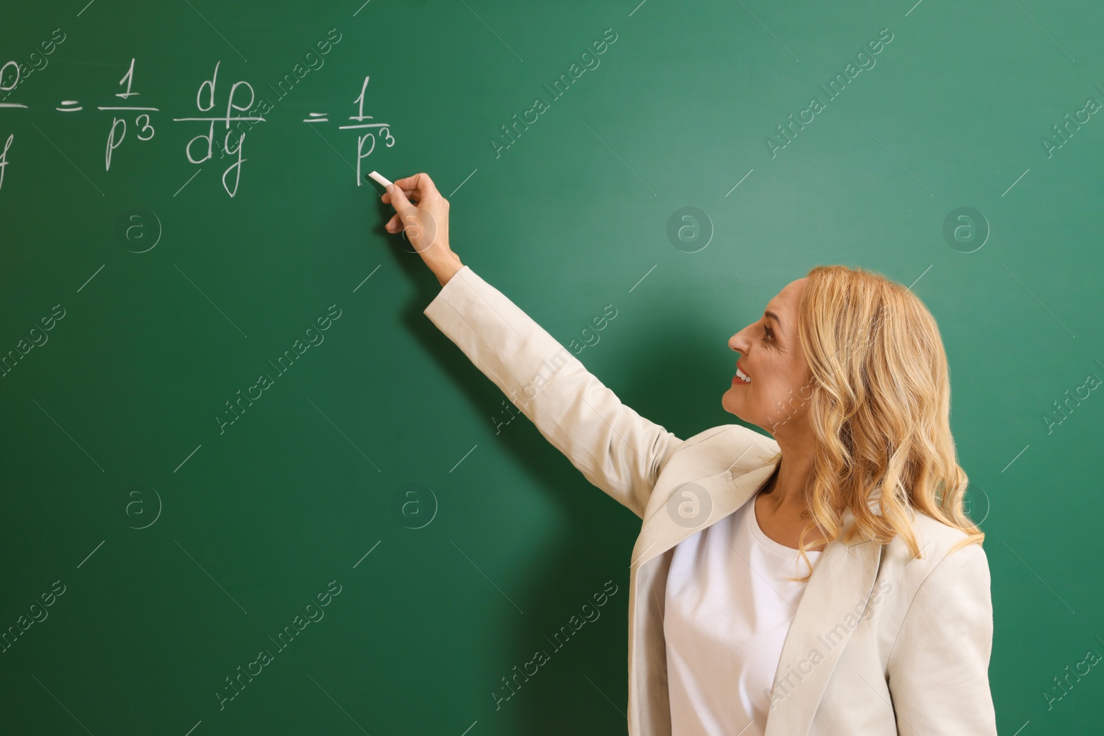 Photo of Professor writing down math equation on green board