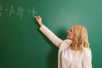 Professor writing down math equation on green board