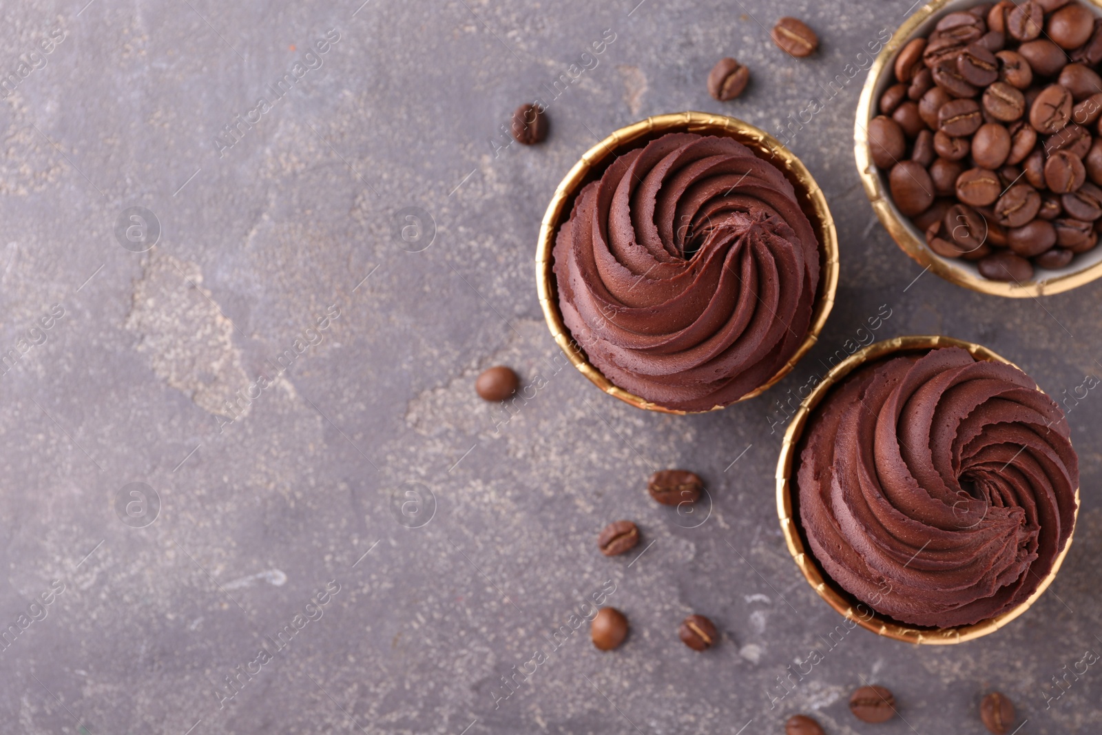 Photo of Delicious chocolate cupcakes and coffee beans on grey textured table, flat lay. Space for text