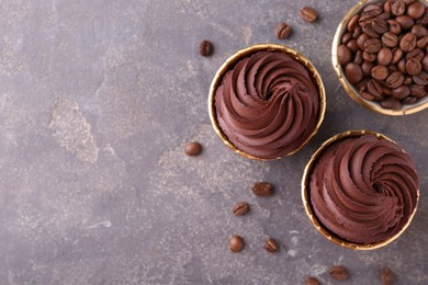 Photo of Delicious chocolate cupcakes and coffee beans on grey textured table, flat lay. Space for text